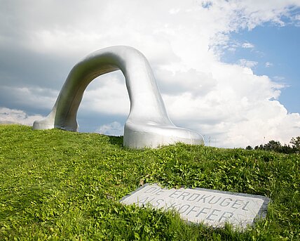 An oversized suitcase handle is positioned on the edge of one of the largest earth pyramids in the sculpture park. 