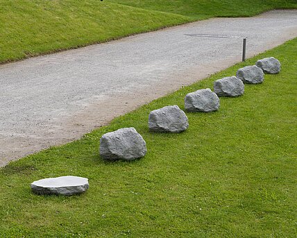 Six concrete stones in a row, modeled on the original limestone. Next to it, at the same distance, a 0.4-fold version of one of the stones.