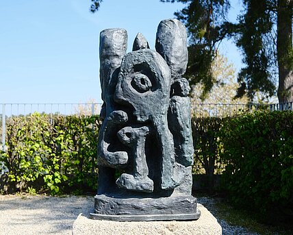 Dark cast on a stone base; abstract shapes with no front or back
