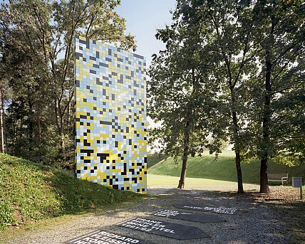 7 m high and 4 m wide, the sculpture grows out of a hill and thus appears to form a similar connection with the park as the surrounding trees. The scientific starting point for the sculpture is the completion of the Human Genome Project in 2001, in which the 3.2 billion base pairs of human DNA were decoded. Schlick replaces the four building blocks of the genome with cheaply produced tiles from Italy in four different colors.