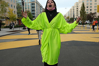 Selma Selman in einem neonfarbenen Kleid im öffentlichen Raum