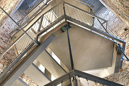 Photo of a concrete and metal staircase in a narrow wooden tower