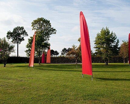 Sails mounted on tilting poles rise up at the rear of the pheasant garden. They move in the wind. 