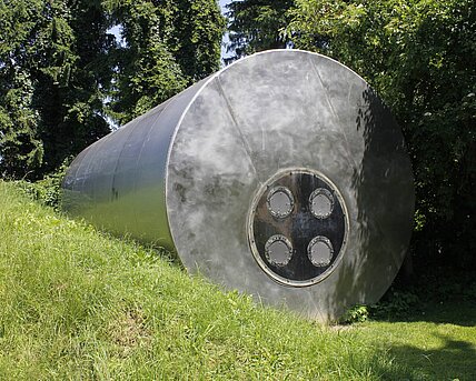 A former steel water silo (11 m long, 4 m in diameter) was reinterpreted by media artist and musician Pinter. It forms the basic structure of this sculpture. Eight integrated bass loudspeakers transform the silo into a musical instrument. The low frequency ranges generate pressure waves that make the sound not only audible but also physically tangible.