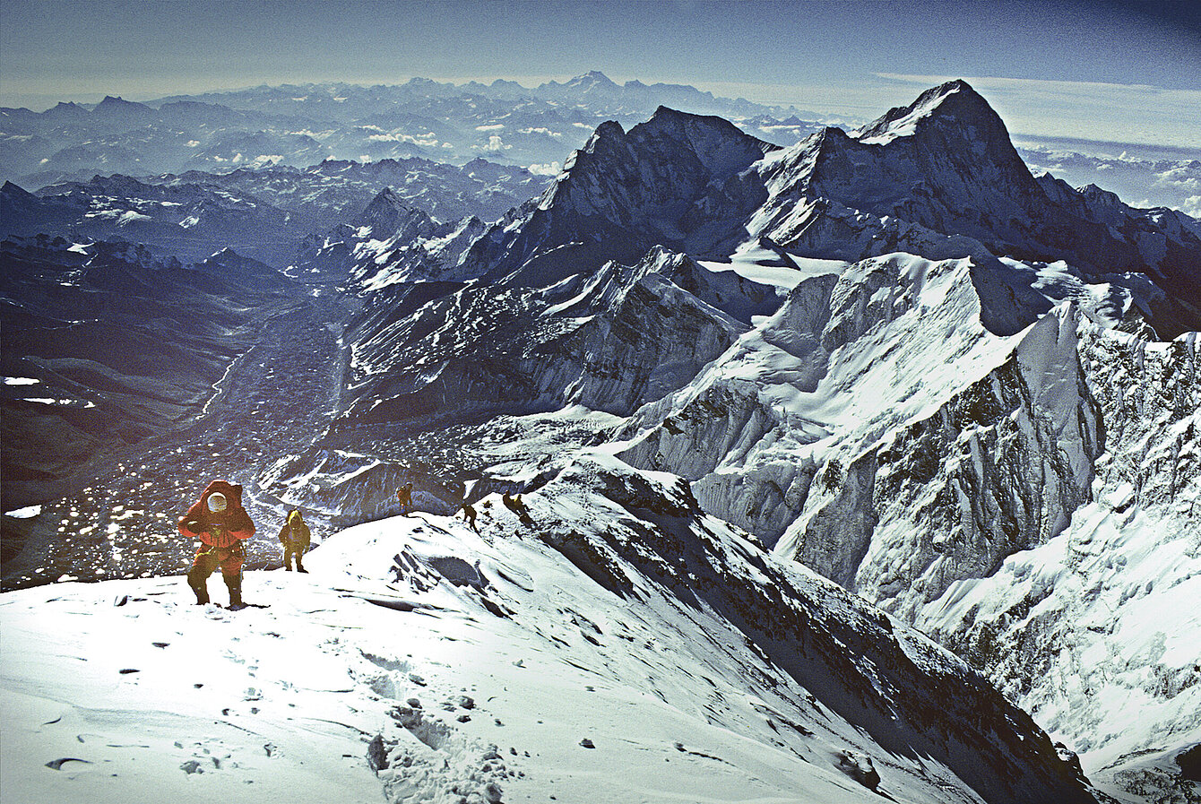 Ein Mann läuft über einen verschneiten Bergkamm.