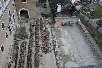 Aerial view of the castle courtyard where paving stones are being laid.