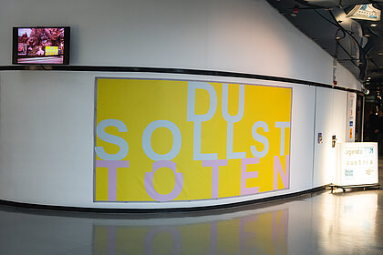 Blick auf das gelbe Banner der Installation "Du sollst töten"