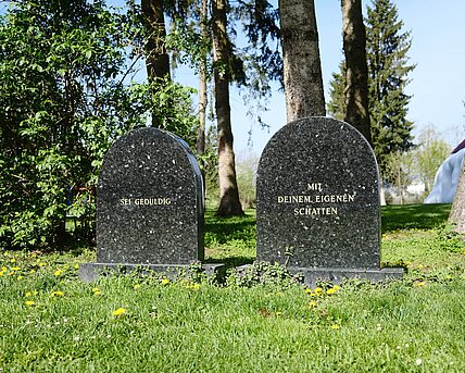 Two gravestones made of smooth stone. The inscription on the first: "Be patient". The inscription on the second: "With your own shadow" [inscriptions are translated from German].
