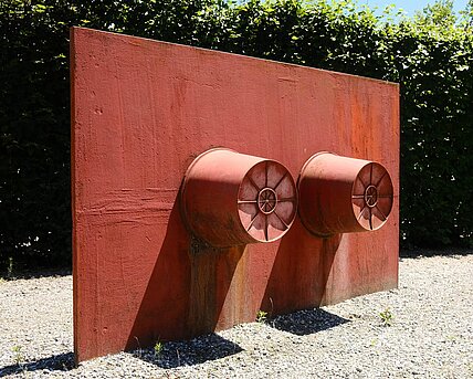 Two metal buckets with their hollow sides fixed to a red metal plate are the basic elements of this sculpture. In the object status of the world of objects, buckets normally stand on the floor. Wurm changes the form of presentation by opening up the base plate and changing the perspective from a floor sculpture to a wall sculpture.
