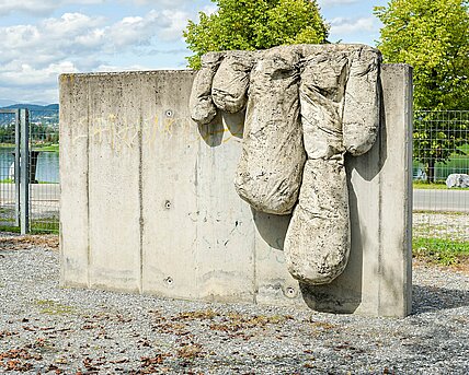 The sculpture by the painter Bohatsch is a vertical, smooth concrete slab with "drops" of concrete hanging down. These resemble fingers and are intended to simulate the paint slowly creeping across the canvas.