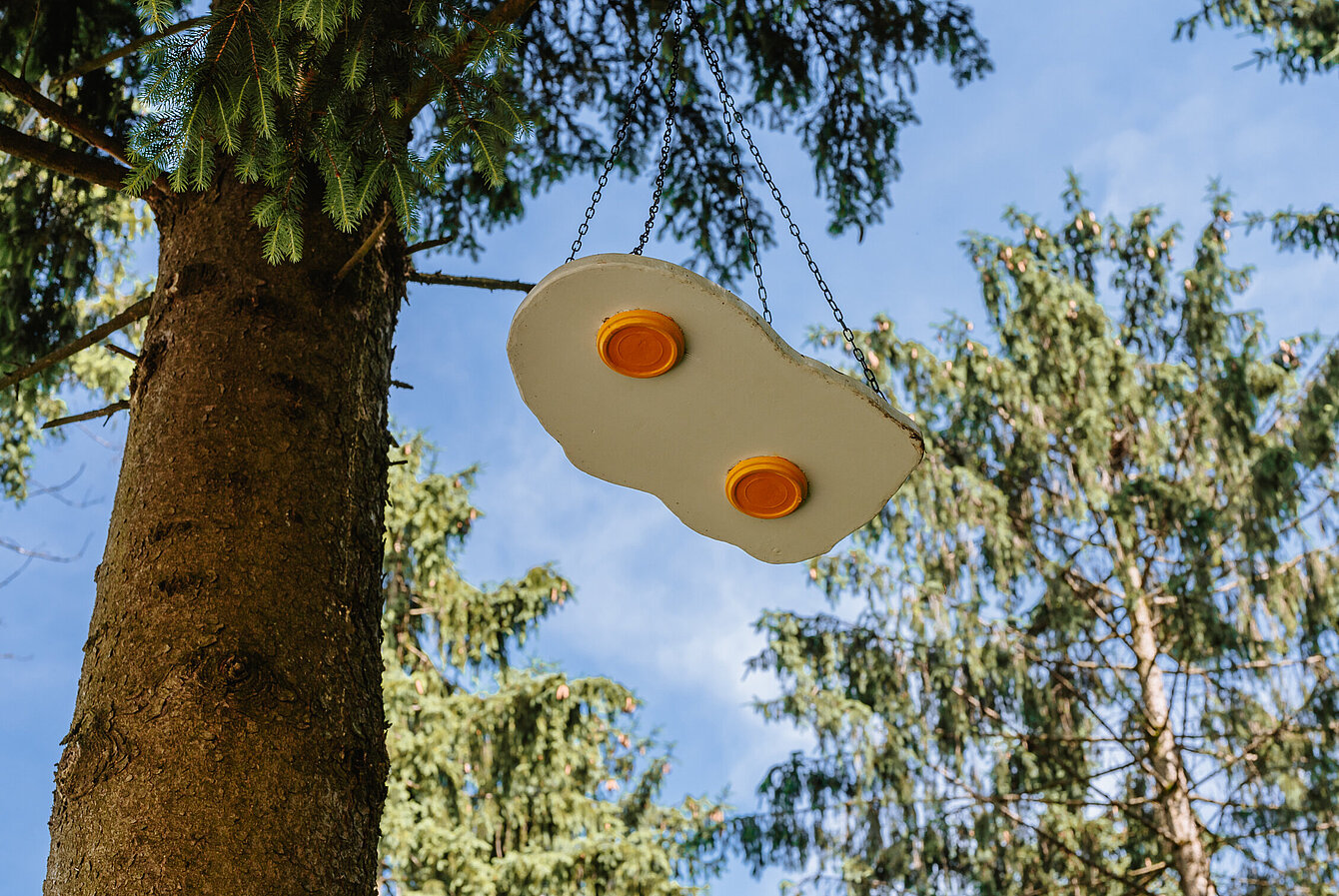 A sunny-side-up-sculpture hangs in the trees.